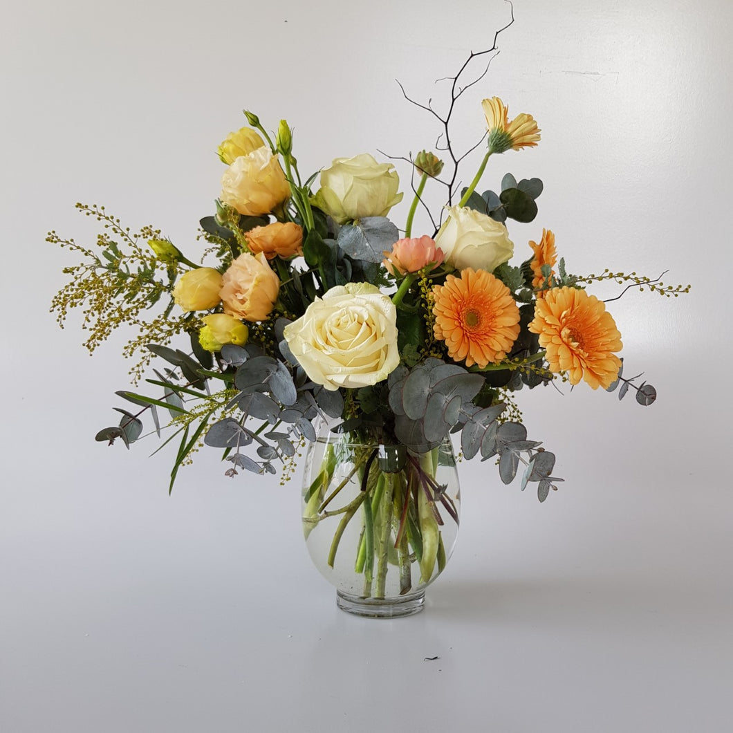 Pastel glass vase arrangement with roses, lisianthus, gerbera and wattle