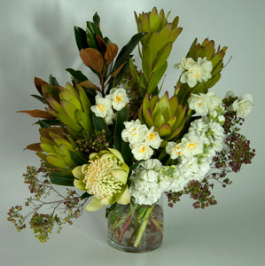 A glass vase arrangement in winter woodland colours that may include, clear whites, creams, taupe, brown, black and fresh greens  Every arrangement is unique and abundant with fresh seasonal blooms.  